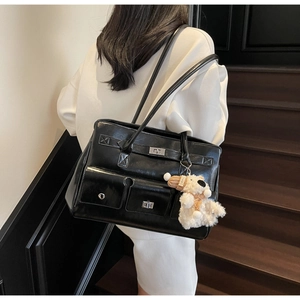 Detail of glossy black shoulder bag with dual front pockets and silver twist locks