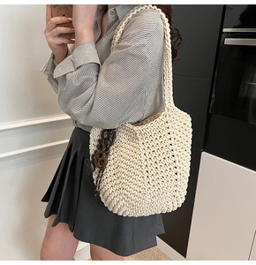 Détail d'un sac cabas tissé crème avec un pendentif décoratif en forme de chocolat