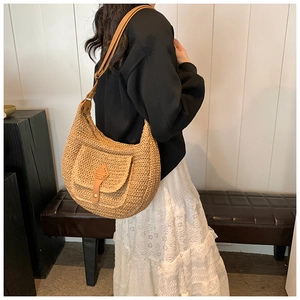 Detail of hand-woven straw shoulder bag with brown leather flap and metal buckle closure