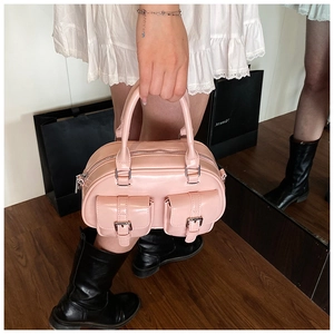 Close-up of a pink glossy bowling bag featuring dual mini pockets and metal buckles