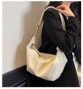 Detail of soft cream leather tote bag with curved stitching and wide strap on model