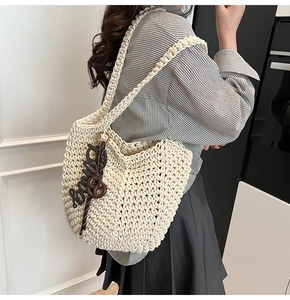 Détail d'un sac cabas en crochet fait main avec texture coton et breloque marron