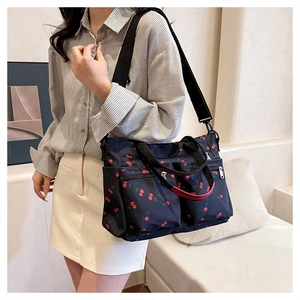 Detail of navy nylon tote bag with cherry print featuring adjustable crossbody strap