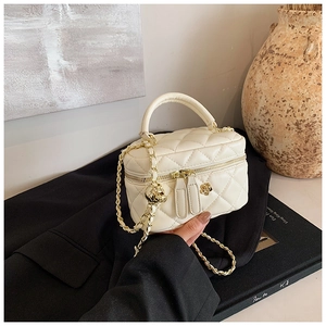 Detail of quilted box bag featuring camellia zipper pull and golden chain strap