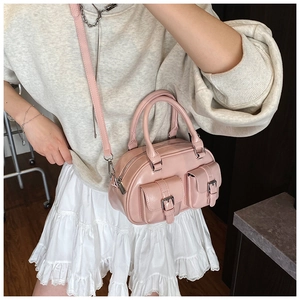 Detailed side view of pink leather bowling bag with flap pockets on female model
