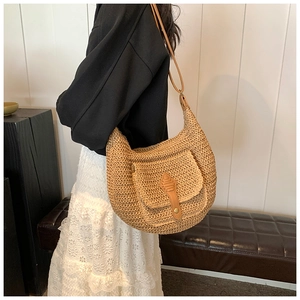 Detail of handwoven straw shoulder bag with brown leather buckle pocket and strap