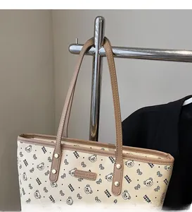 Dettaglio della grande borsa tote con stampa orsetto, sottili tracolle marroni e rivetti
