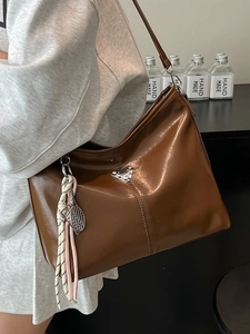 Brown faux leather hobo bag with glossy finish and sporty tennis racket charm detail