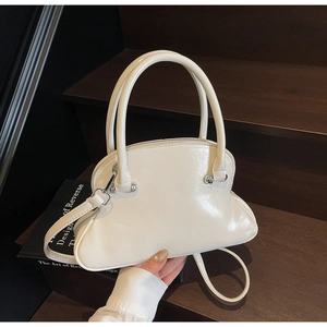 Detailed close-up of cream off-white glossy patent leather handbag on wooden steps
