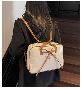 Close-up of cream oil wax leather backpack with brown straps and bow detail on model