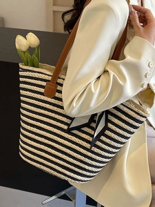 Fashionable black and white striped straw tote bag with brown leather straps for beach vacation