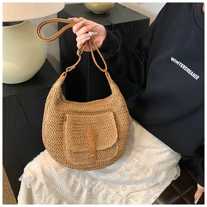 Detailed view of woven straw shoulder bag featuring textured flap pocket and leather accents