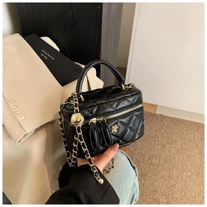 Close-up of black quilted leather box bag with gold flower clasp and chain strap