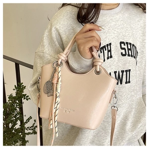 Dettaglio della borsa a secchiello rosa chiaro con manico rotondo e charm tennis