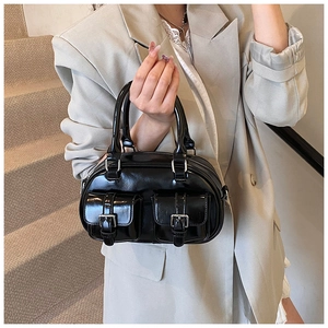 Close-up of black patent leather handbag featuring dual front pockets and silver buckles