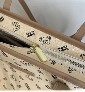 Dettaglio della cerniera scorrevole e della stampa dell'orso sulla borsa tote beige