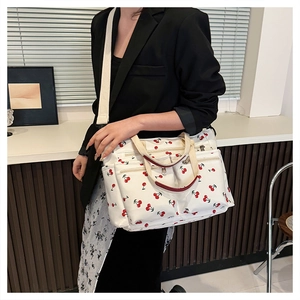 Detail shot of a large canvas tote with cherry prints showing multiple zipper compartments