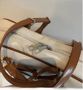 Detail shot of smooth silver dual zippers on a cream and brown PU leather tote bag