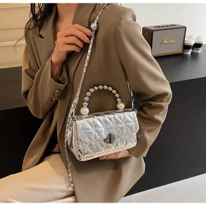 Detail of silver quilted handbag featuring pearl handle and metallic chain strap
