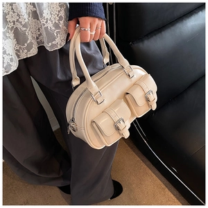 Detail of cream bowling bag showing dual front buckle pockets and silver metal zippers