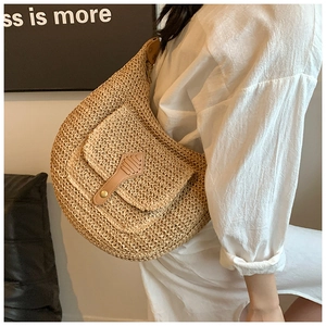 Detail of hand-woven straw crossbody bag with leather flap and metal buckle on a shoulder strap