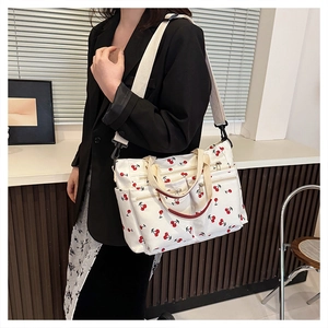 Detail view of canvas cherry print tote bag with multiple zip pockets and shoulder strap