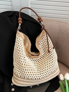 Borsa tote intrecciata boho con perline in legno scuro su un divano grigio