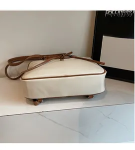 Detail of cream white tote bag with brown leather knot and protective metal feet
