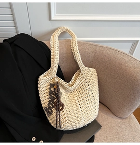 Vue détaillée de la texture tissée crème et du gland décoratif sur le sac à bandoulière