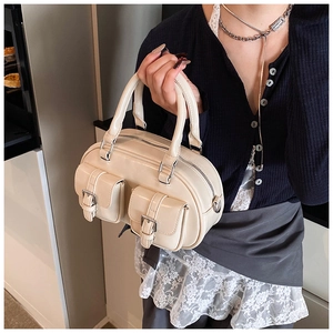 Detail view of cream white bowling bag featuring two cargo front pockets and silver buckles
