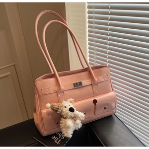 Close-up of pink faux leather shoulder bag with plush puppy charm and silver twist lock