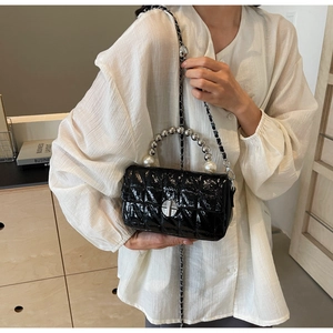 Macro shot of black quilted faux leather bag featuring silver bead and pearl handle detail