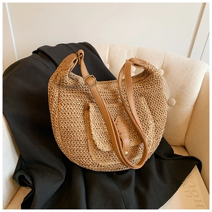 Detail of hand-woven straw saddle bag with dark brown leather strap and mesh texture