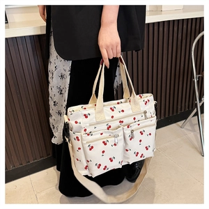 Detailed view of the white canvas cherry print tote bag with multiple zipper pockets