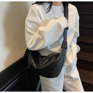 Detail view of black crescent tote bag featuring matte leather texture and silver buckle