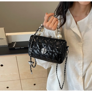 Detail of black patent leather bag with quilted pattern and large pearl handle accent