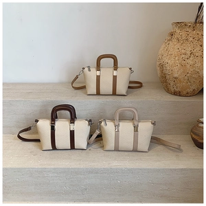 Detailed view of three minimalist woven crossbody bags in neutral tones on stone steps
