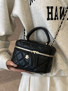 Black quilted box bag with gold camellia floral clasp and chain strap on casual outfit