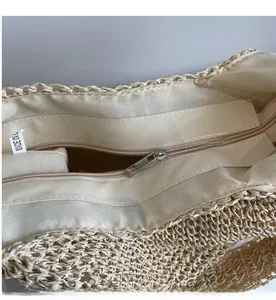 Detail shot of the smooth metal zipper closure and interior lining of the woven straw tote