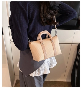 Detail showing the light apricot woven texture and double handles of the Boston bag