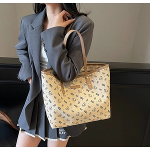 Dettaglio della borsa tote beige con orsetti indossata da modella in blazer grigio