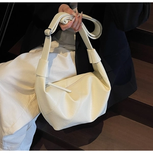Detail of white matte leather hobo bag with diagonal stitching and knotted shoulder strap