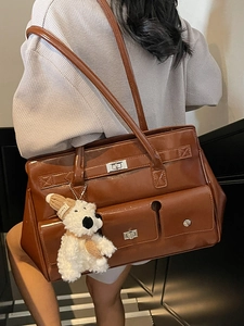 Polished brown leather shoulder bag with metallic lock and plush bear charm accent