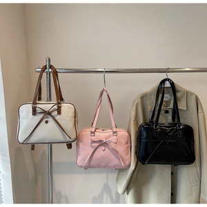 Three bow-knot tote bags in cream, pink, and black displayed on metal stands