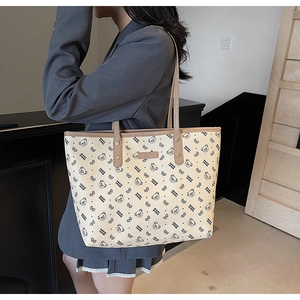 Dettaglio di borsa tote con stampa orsetto e bordo marrone indossata da una modella