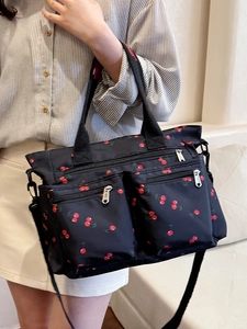 Black nylon tote bag with red cherry print, featuring multi-zipper pockets and shoulder strap