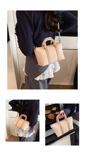 Detail of beige woven square handbag featuring metal buckles and detachable shoulder strap