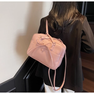 Detail showing the pink ballet-style bow tote with versatile shoulder straps on a model