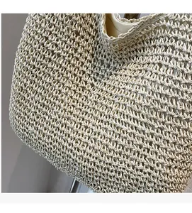 Detail of hand-woven straw tote bag showing intricate hollow pattern and fabric lining