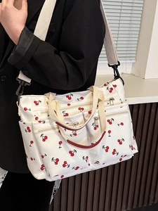 White canvas tote bag with red cherry prints featuring multiple pockets and wide strap